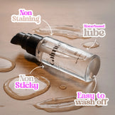 Clear bottle of water-based lubricant with text highlighting features on a wooden surface.